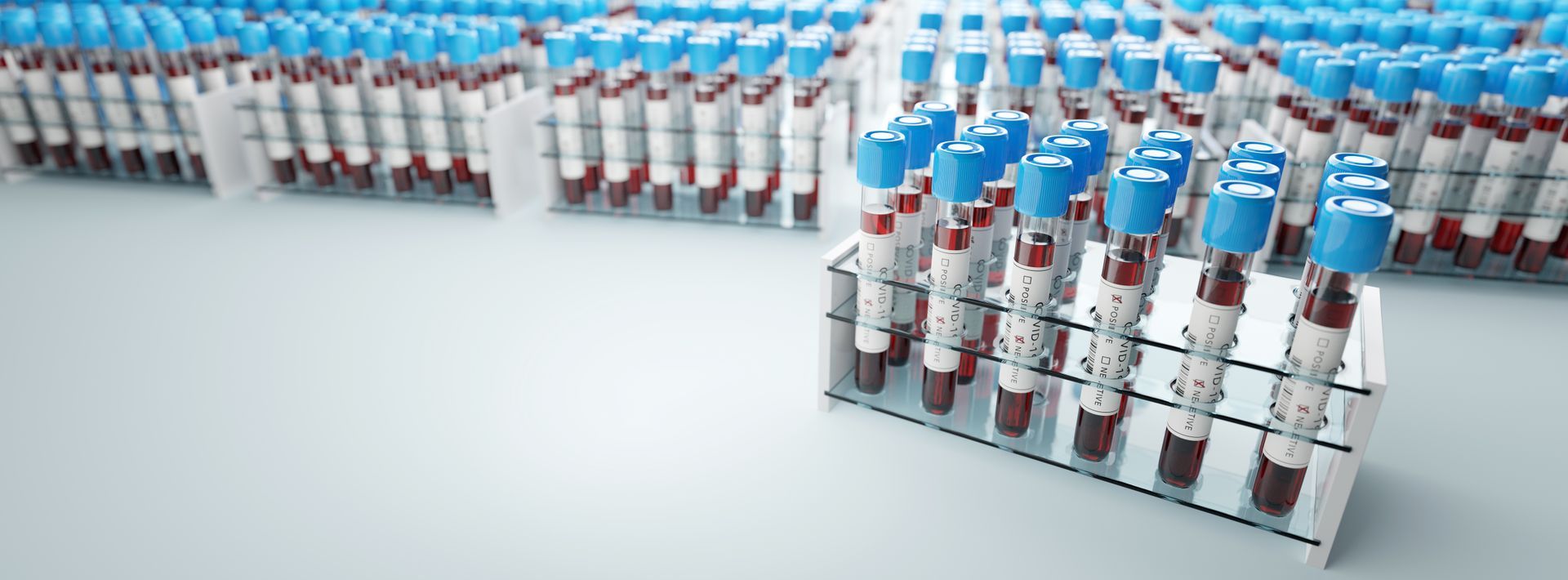 Des rangées de flacons de vaccin à bouchon bleu sur une table de laboratoire propre.