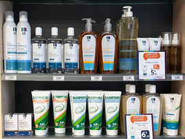 Rayon de magasin avec un assortiment de flacons, tubes et boîtes de produits nettoyants et de soins corporels dans des emballages bleus, blancs et oranges.