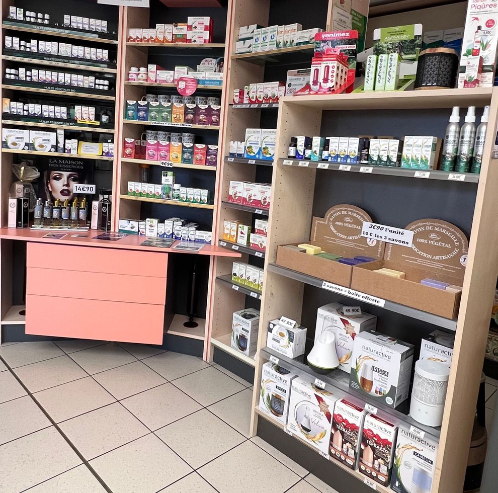 Des étagères remplies de produits emballés dans une petite allée de magasin, avec un sol carrelé et un comptoir rose.