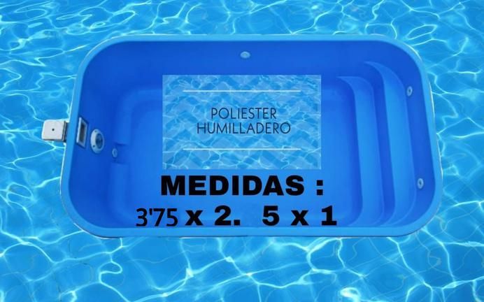 Piscina rectangular de color azul, rodeada de césped artificial verde y borde de madera, frente a una pared blanca.