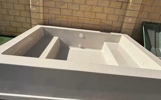 Piscina de plástico azul con escalones curvos adjuntos.