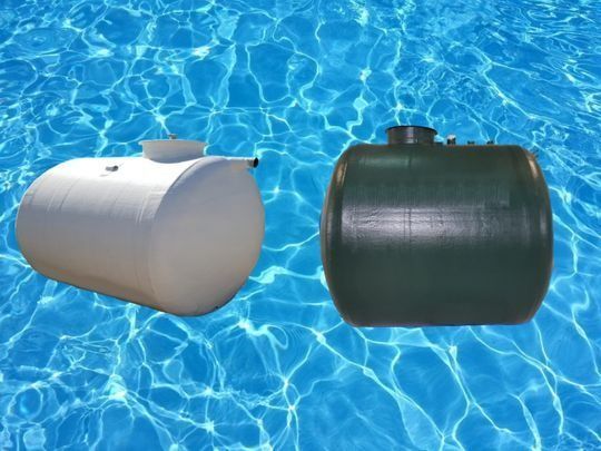 Dos tanques de agua, uno blanco y otro verde, sobre un fondo de agua azul.