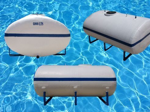 Tres tanques de agua blanca con detalles azules, cada uno sobre soportes de metal, sobre un fondo de agua azul.