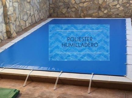 Cubierta azul tensada sobre una piscina, sujeta con cordones blancos. Texto superpuesto: 