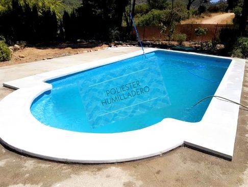 Piscina con agua azul y marco de hormigón blanco, al aire libre.