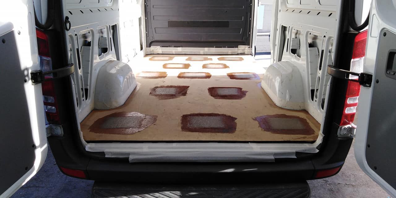 Vista interior de una camioneta de carga con piso de madera instalado, vista desde las puertas traseras abiertas.