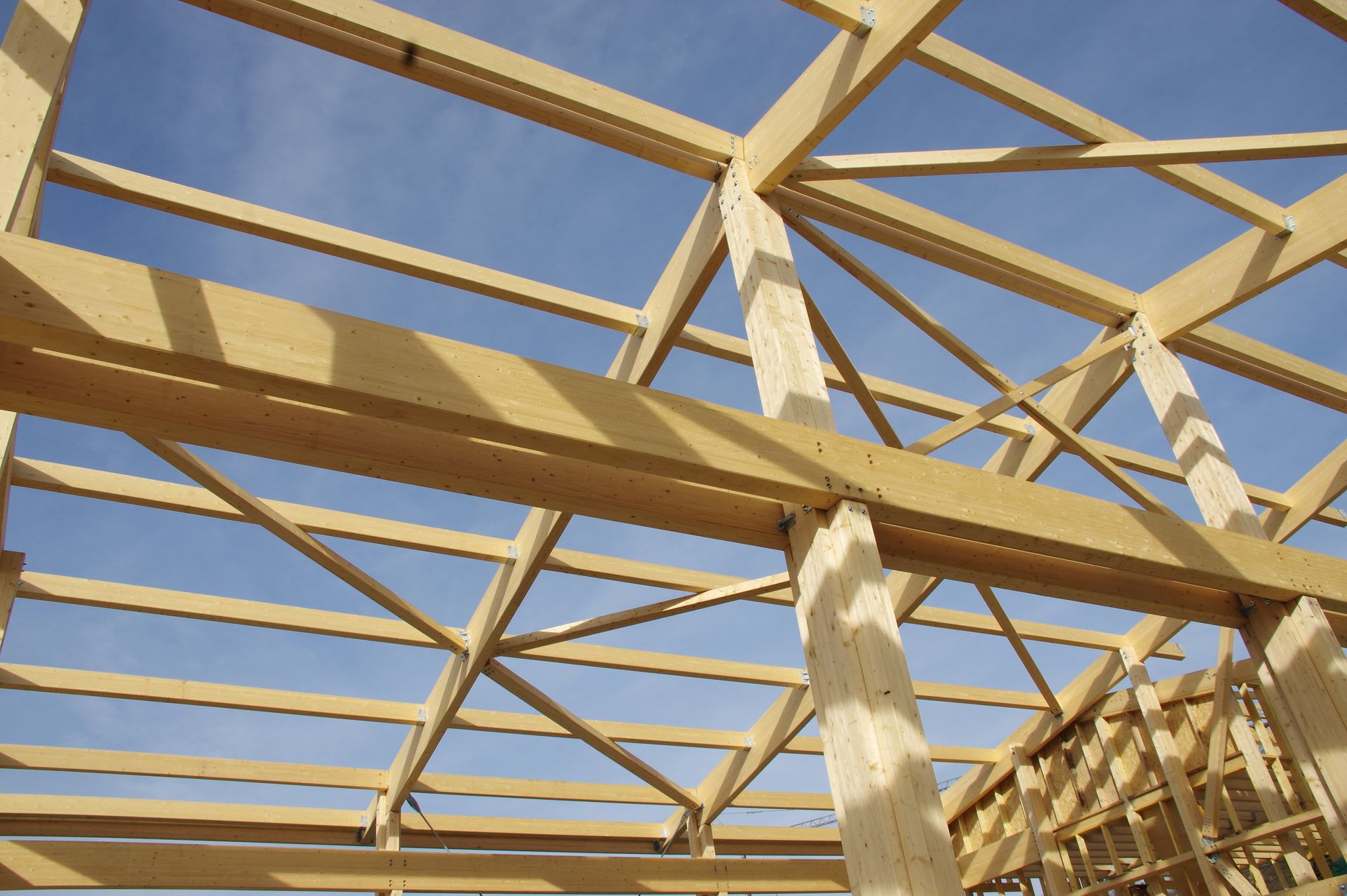 Charpente en bois se détachant sur un ciel bleu ; poutres et supports formant la structure du toit d'un bâtiment.