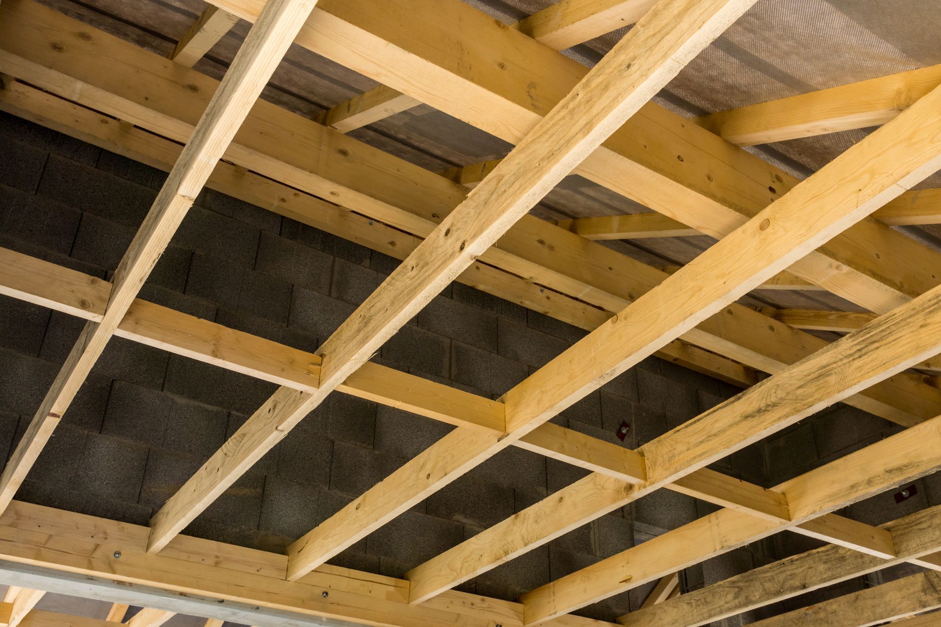 Des poutres en bois forment une charpente contre des murs et la couverture.