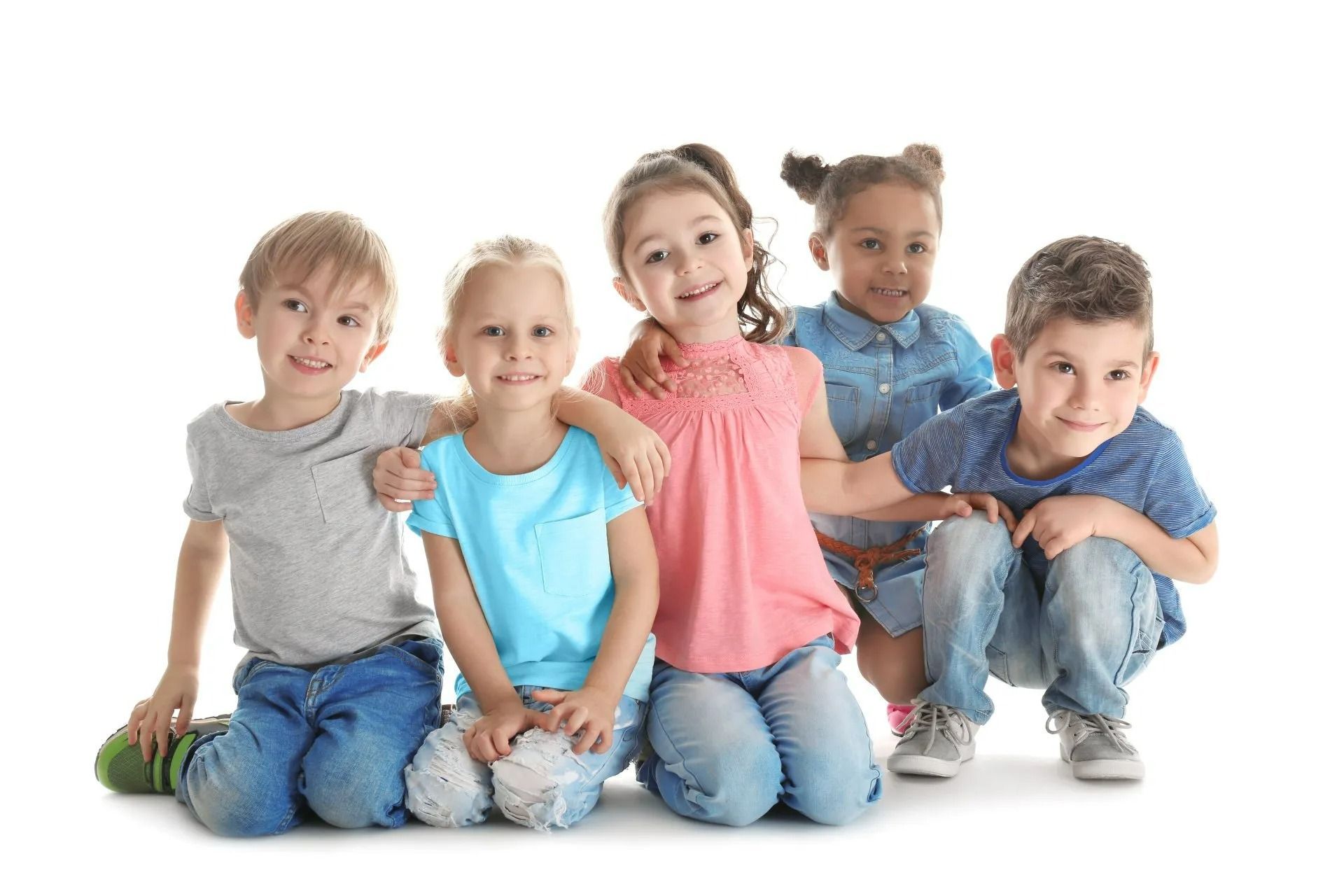 Cinq enfants souriants, assis ensemble sur un fond blanc, se tenant par les bras.