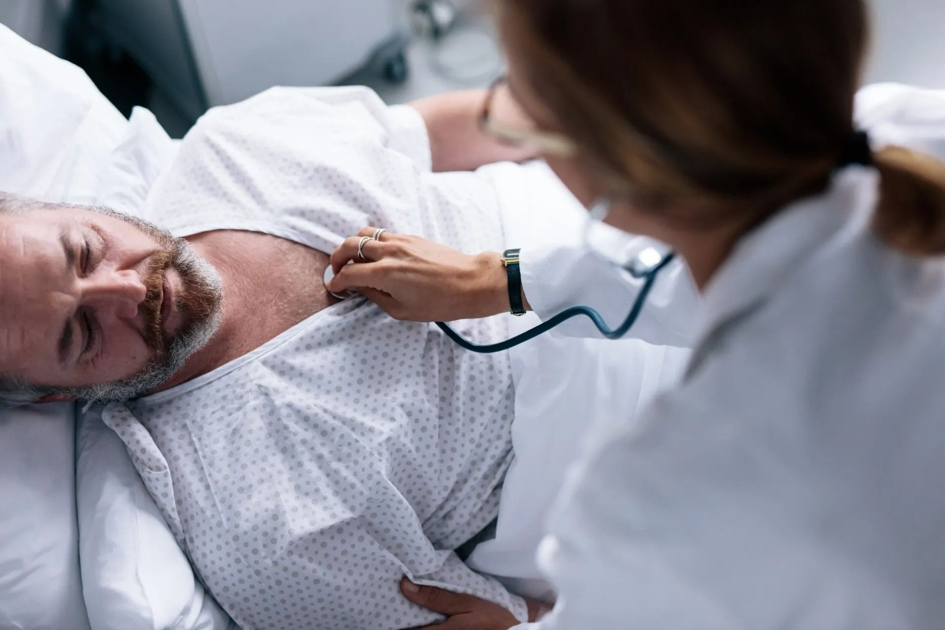 Personnel médical examinant un patient dans un lit d'hôpital.