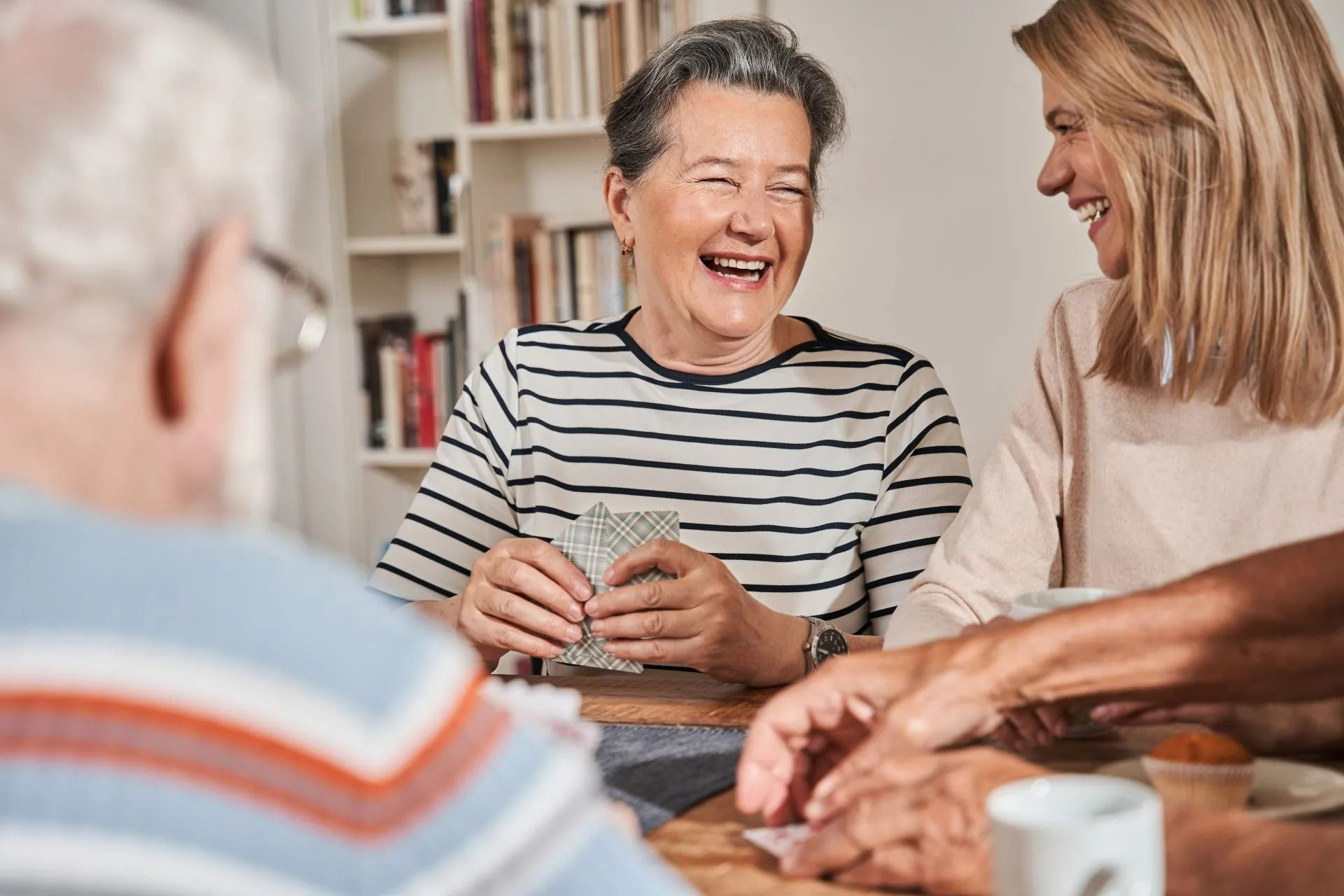 Des gens rient et discutent autour d'une table lors d'une partie de cartes.
