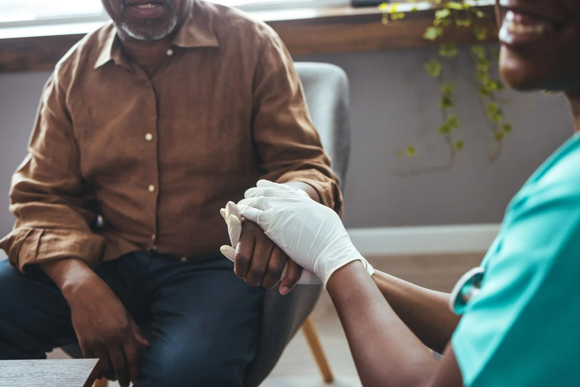 Un professionnel de santé tient la main d'un patient lors d'une consultation médicale.