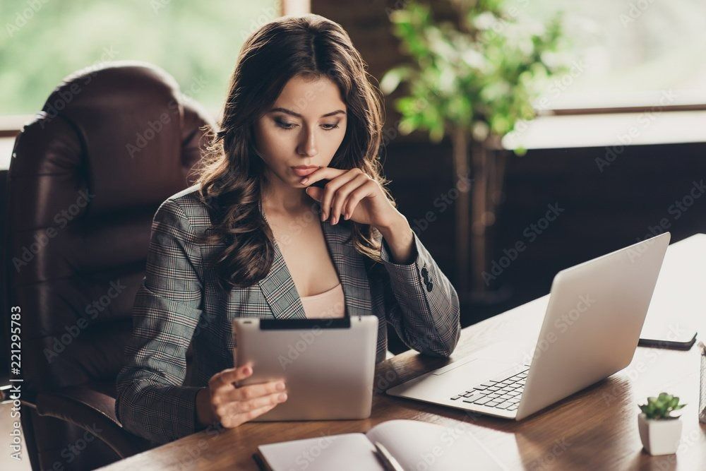 Une femme installée à son bureau travaille sur une tablette numérique et un ordinateur portable.