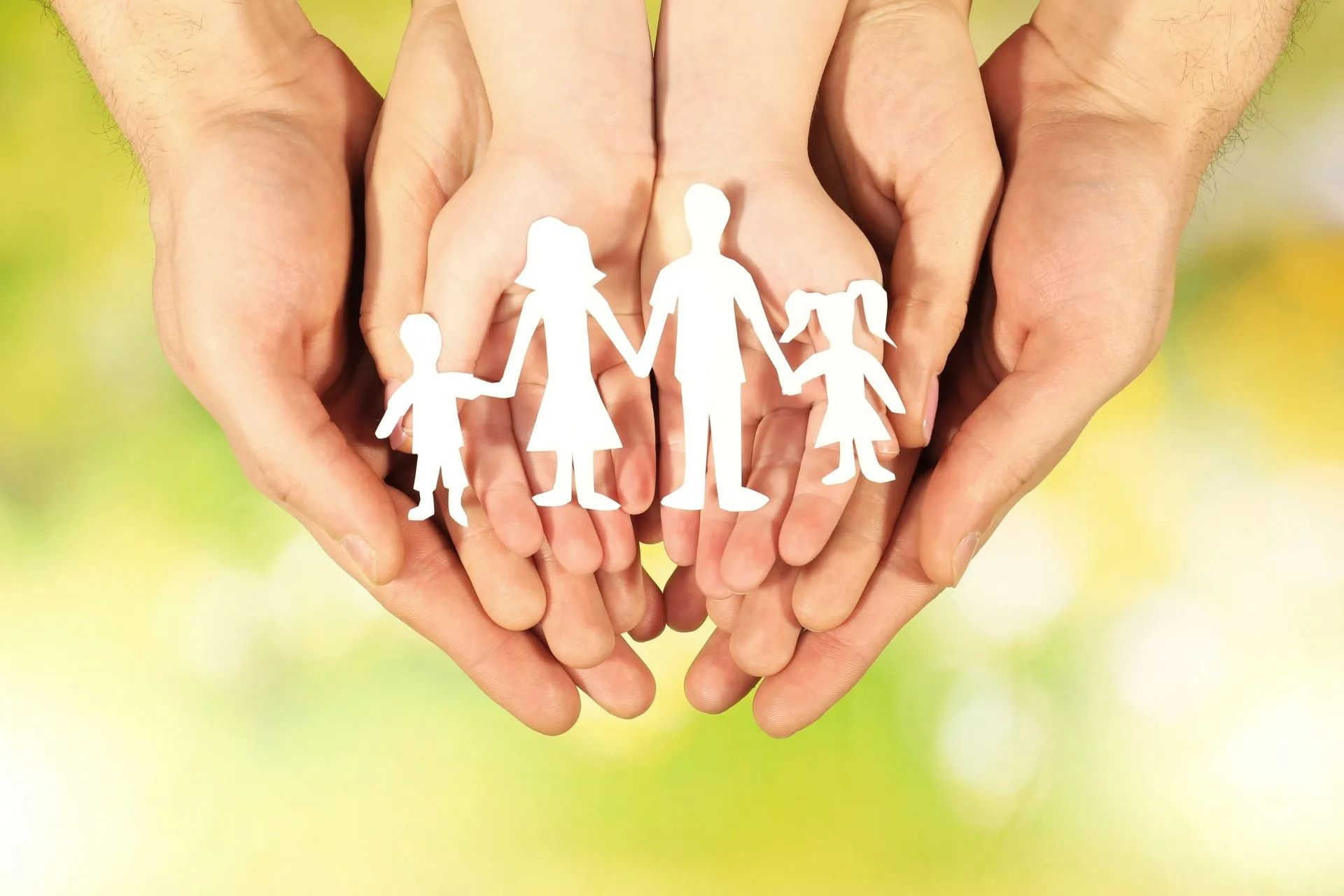 Des mains tiennent des silhouettes de papier, découpées en forme de famille.