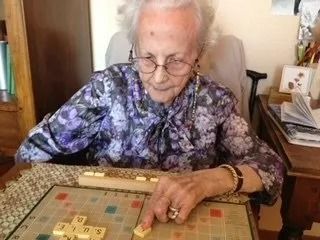 Une femme âgée joue au Scrabble.