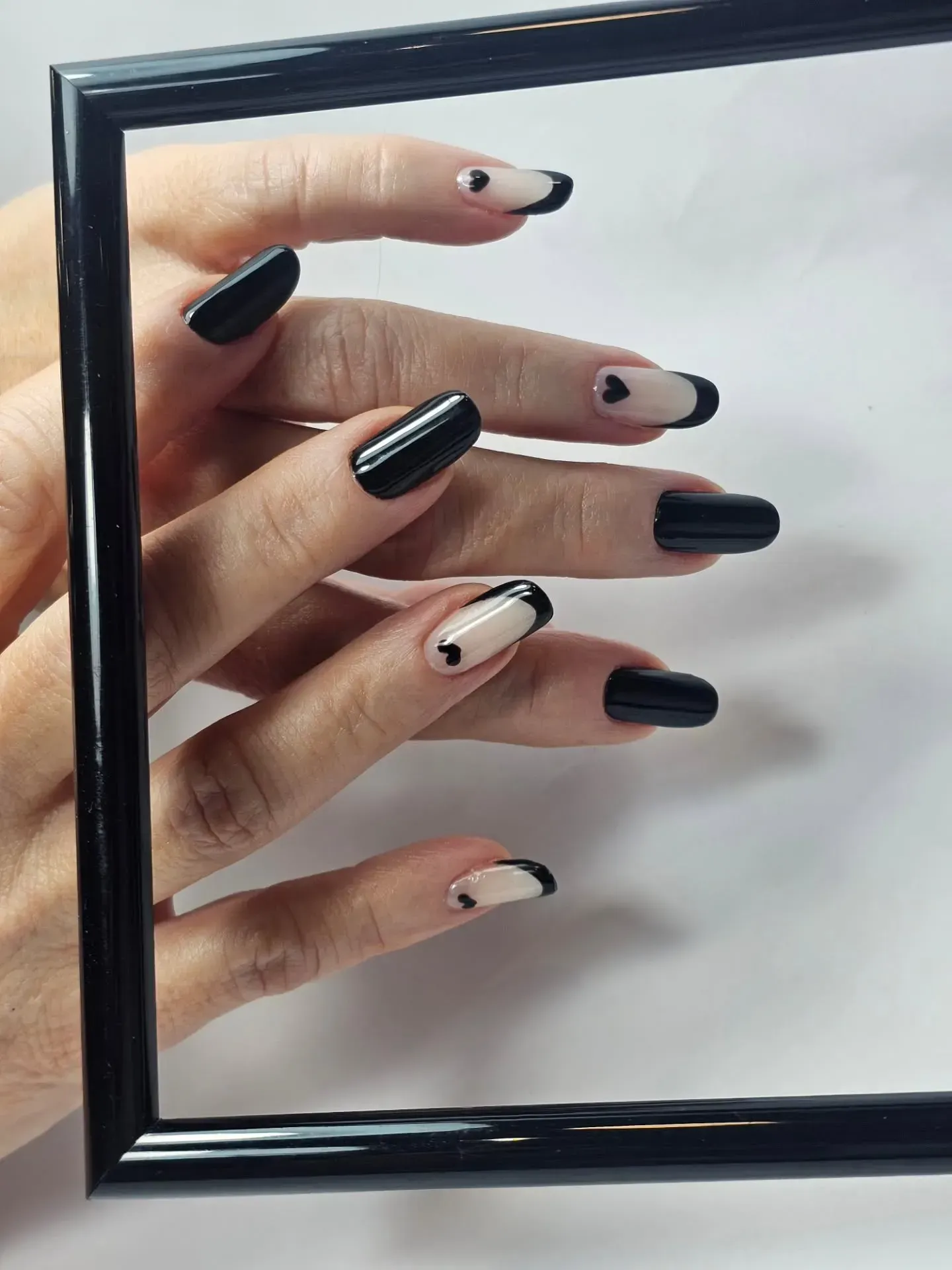 Manos con uñas largas, pintadas en tonos burdeos y nude, sujetando una tela blanca.
