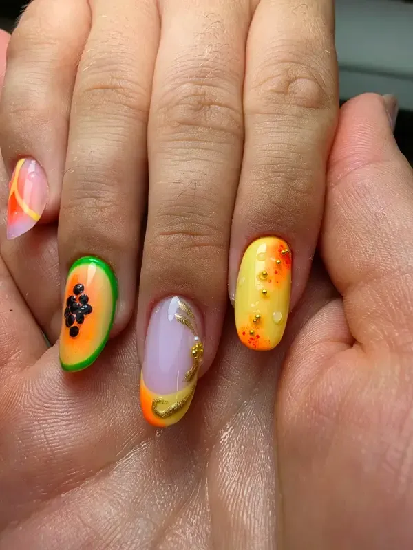 Primer plano de un diseño de uñas neón colorido en una mano, con motivos naranjas, verdes, morados y amarillos.