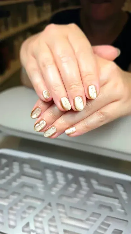 Manos con las uñas arregladas apoyadas sobre una bandeja para teclado, luciendo un diseño de rayas rosas pálidas y blancas.