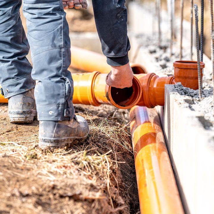 Un tuyau orange porté par un technicien