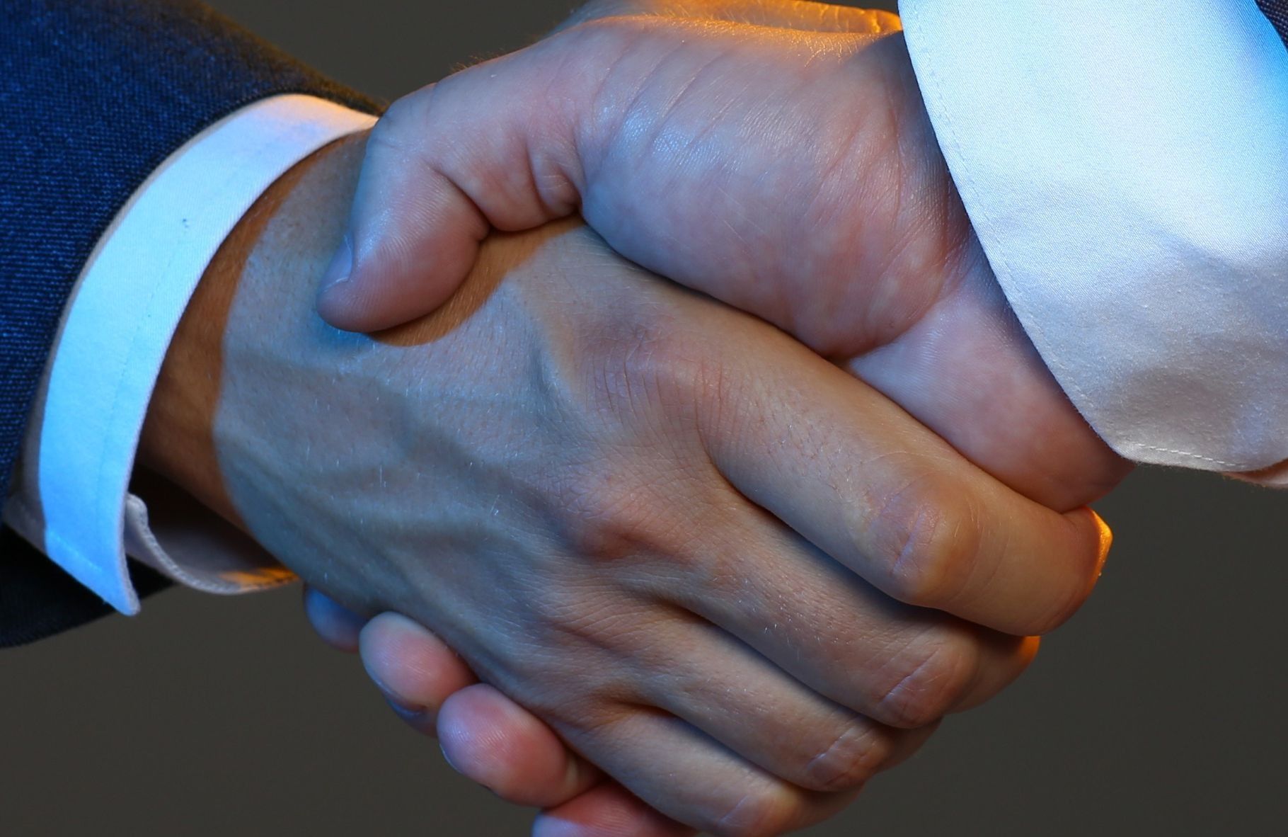 Un hombre con traje y corbata le da la mano a otro hombre.