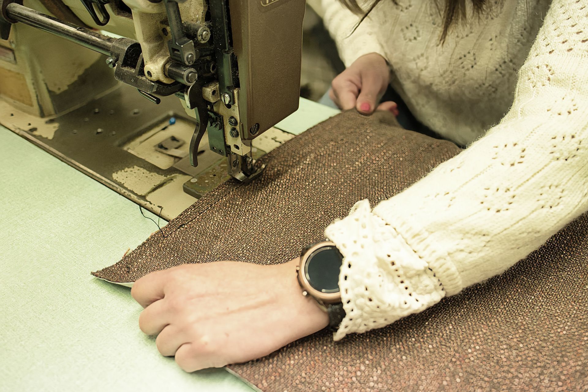 Une couturière sur la finition d'une tapisserie de fauteuil.
