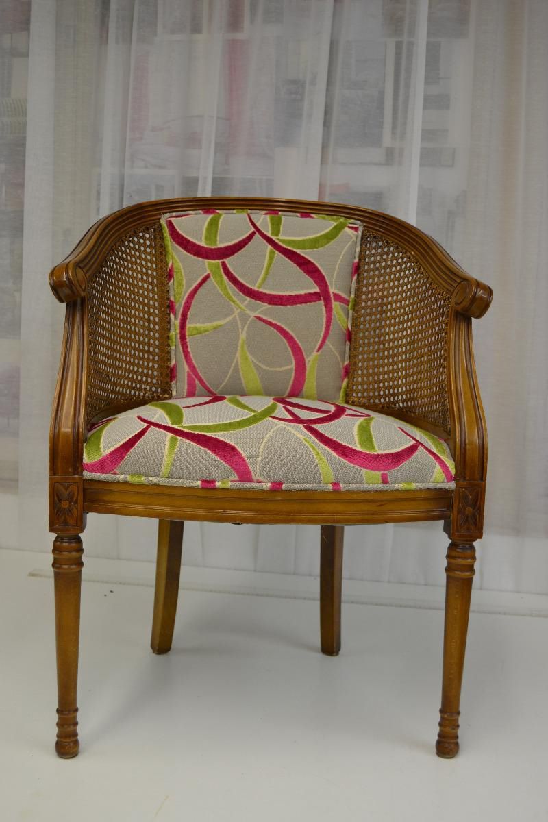 Un fauteuil en bois et rotin avec tissus aux motifs tendances.