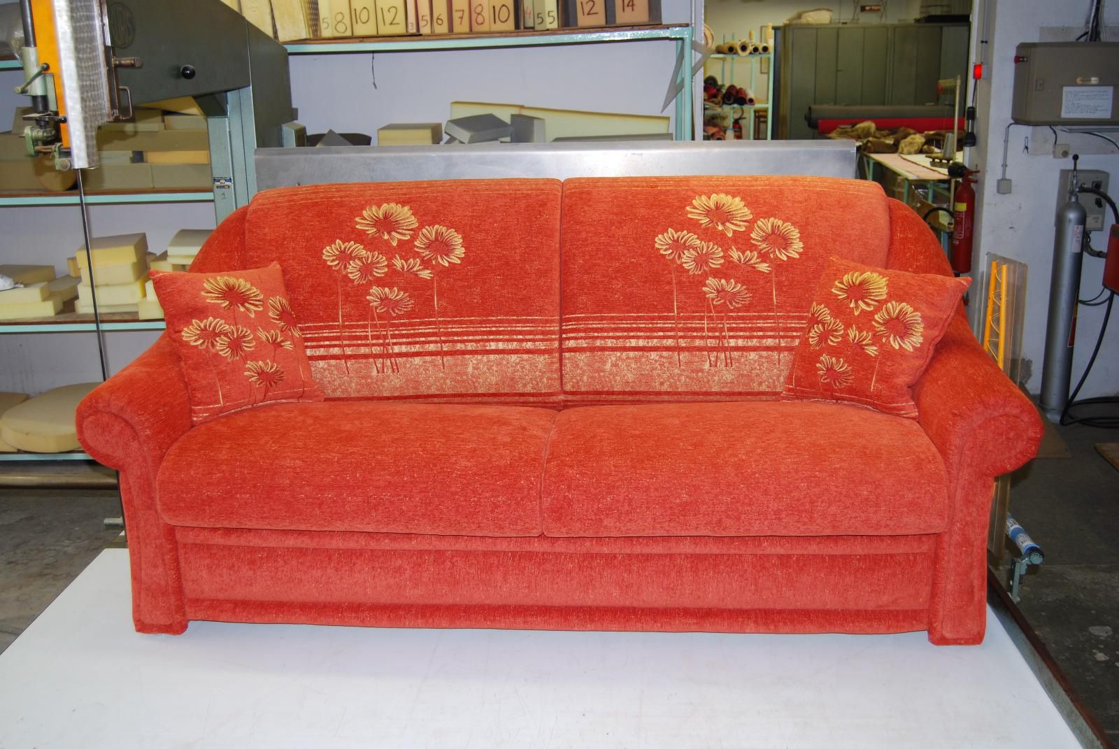 Canapé rouge avec des motifs à fleurs jaunes.