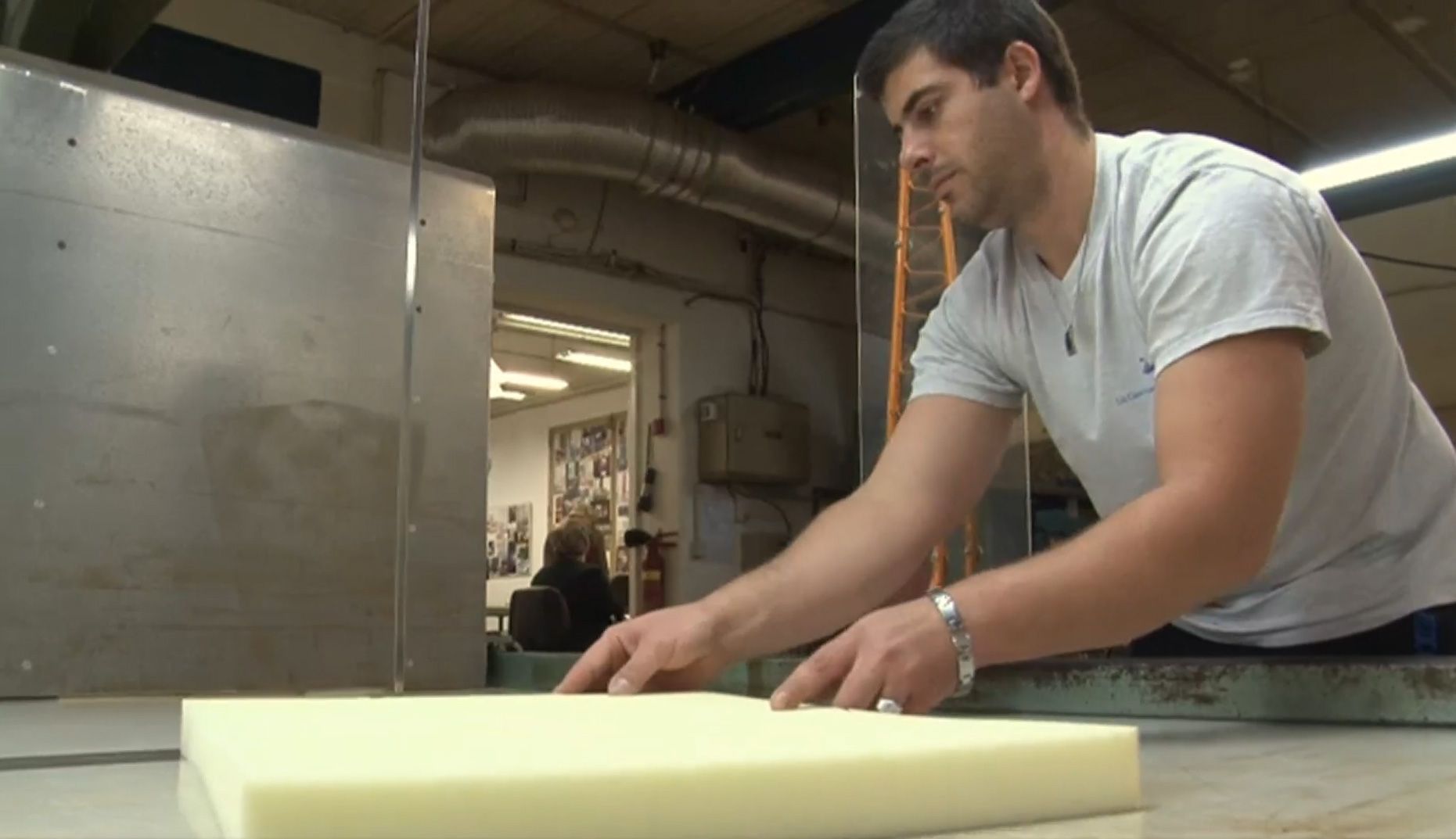 Un artisan de chez Erton découpant de la mousse de coussin.