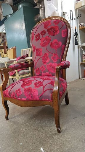 Fauteuil avec tapisserie pourpre avec des motifs de fleurs.