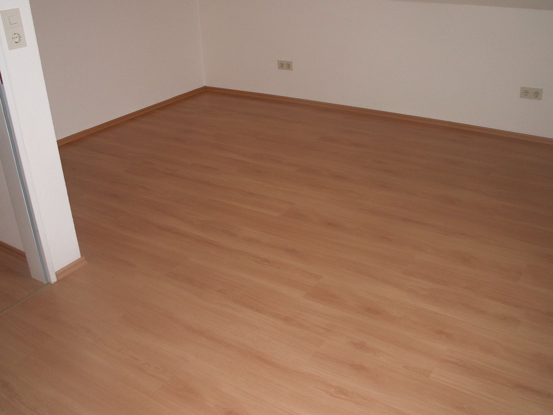 Ein leerer Raum mit Holzboden und weißen Wänden