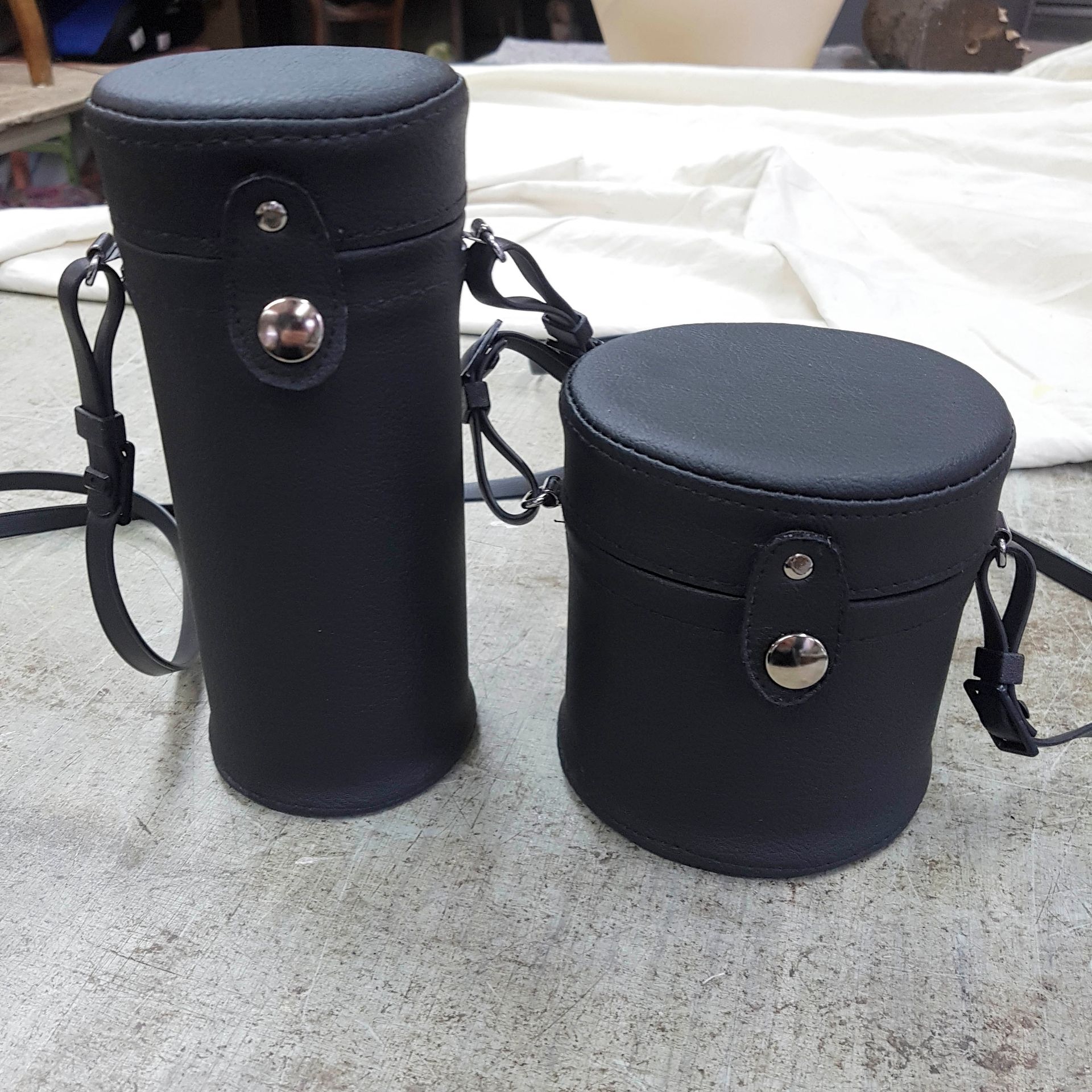 Zwei schwarze Koffer mit Riemen liegen auf einem Teppich