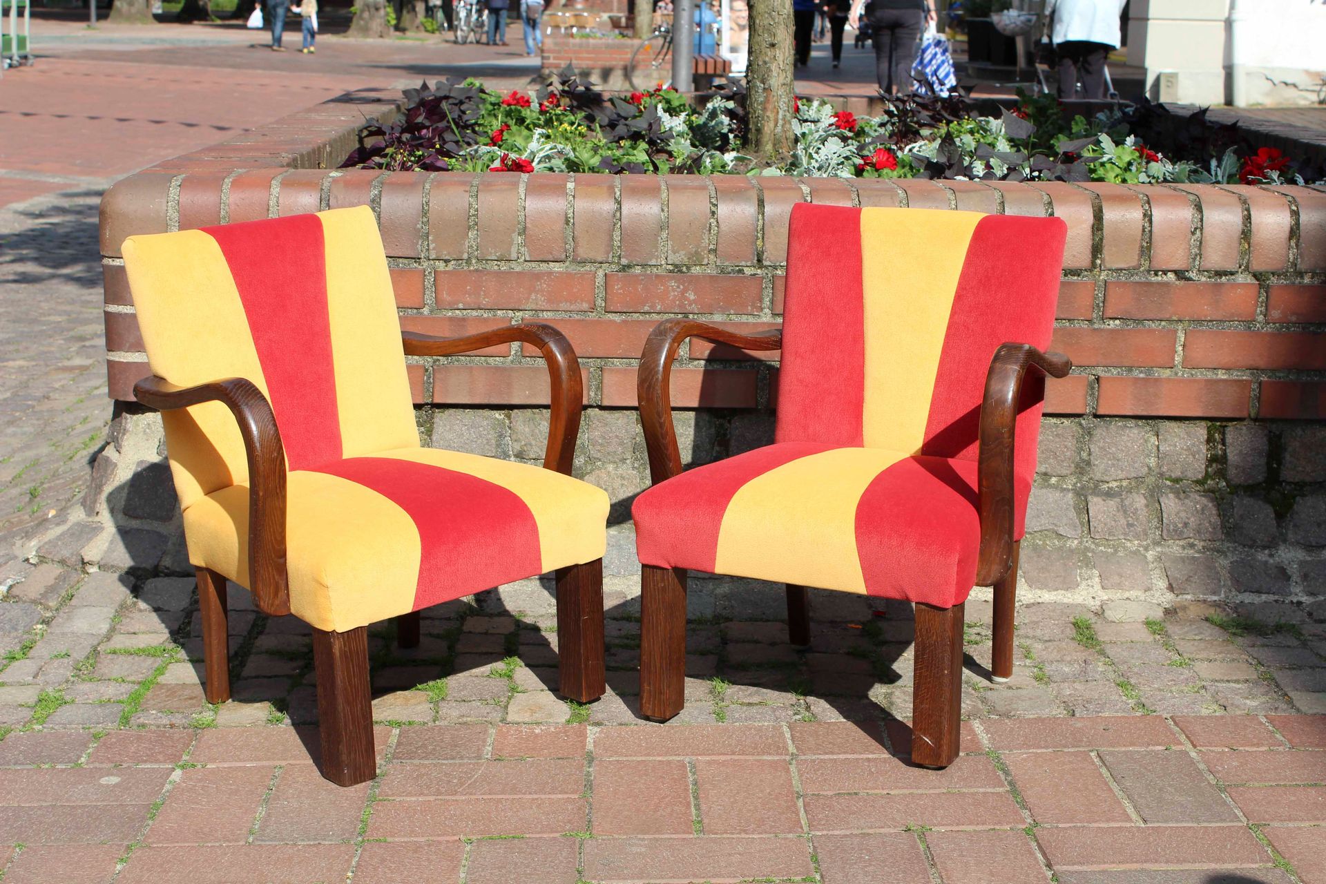 Zwei rote und gelbe Stühle stehen auf einem gemauerten Gehweg