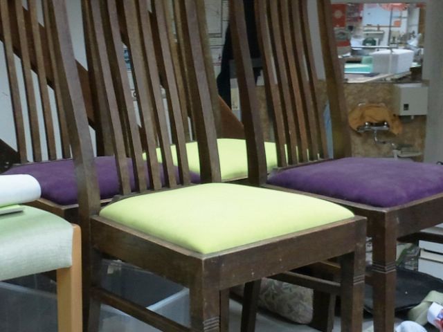 Eine Reihe Holzstühle mit lila und gelben Kissen