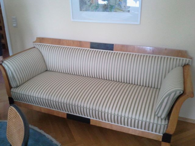 In einem Wohnzimmer steht ein gestreiftes Sofa neben einem Stuhl.