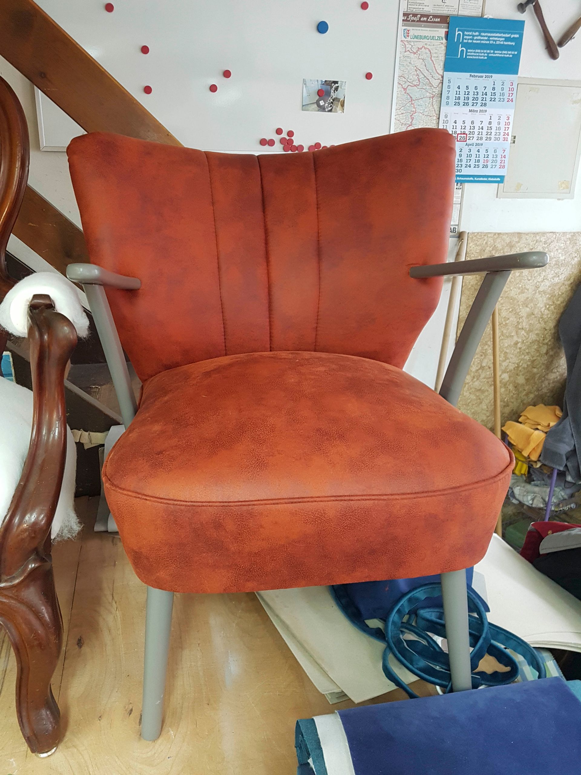 Ein roter Stuhl steht auf einem Holzboden in einem Zimmer.