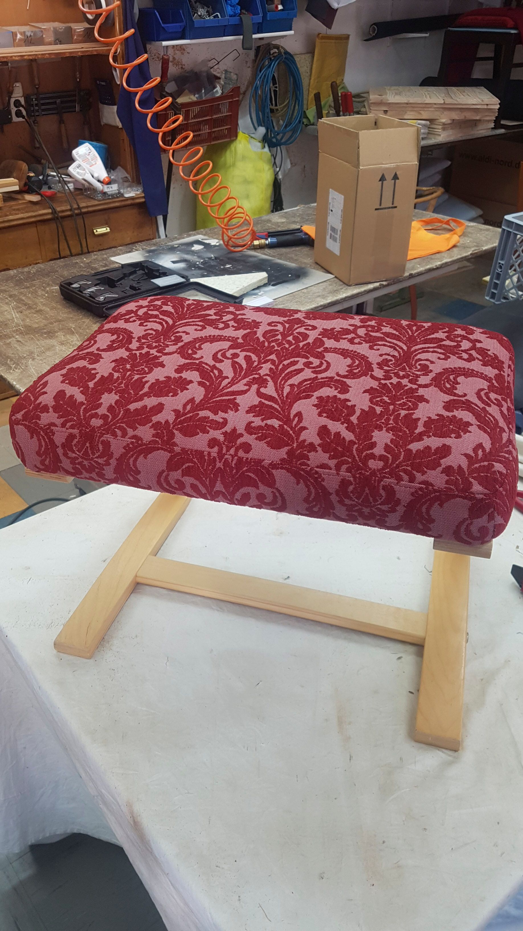 Auf einem weißen Tisch steht ein roter Ottomane.