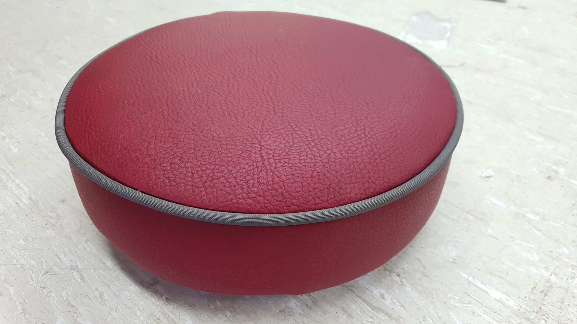 Auf einem weißen Tisch steht ein roter Ottomane.