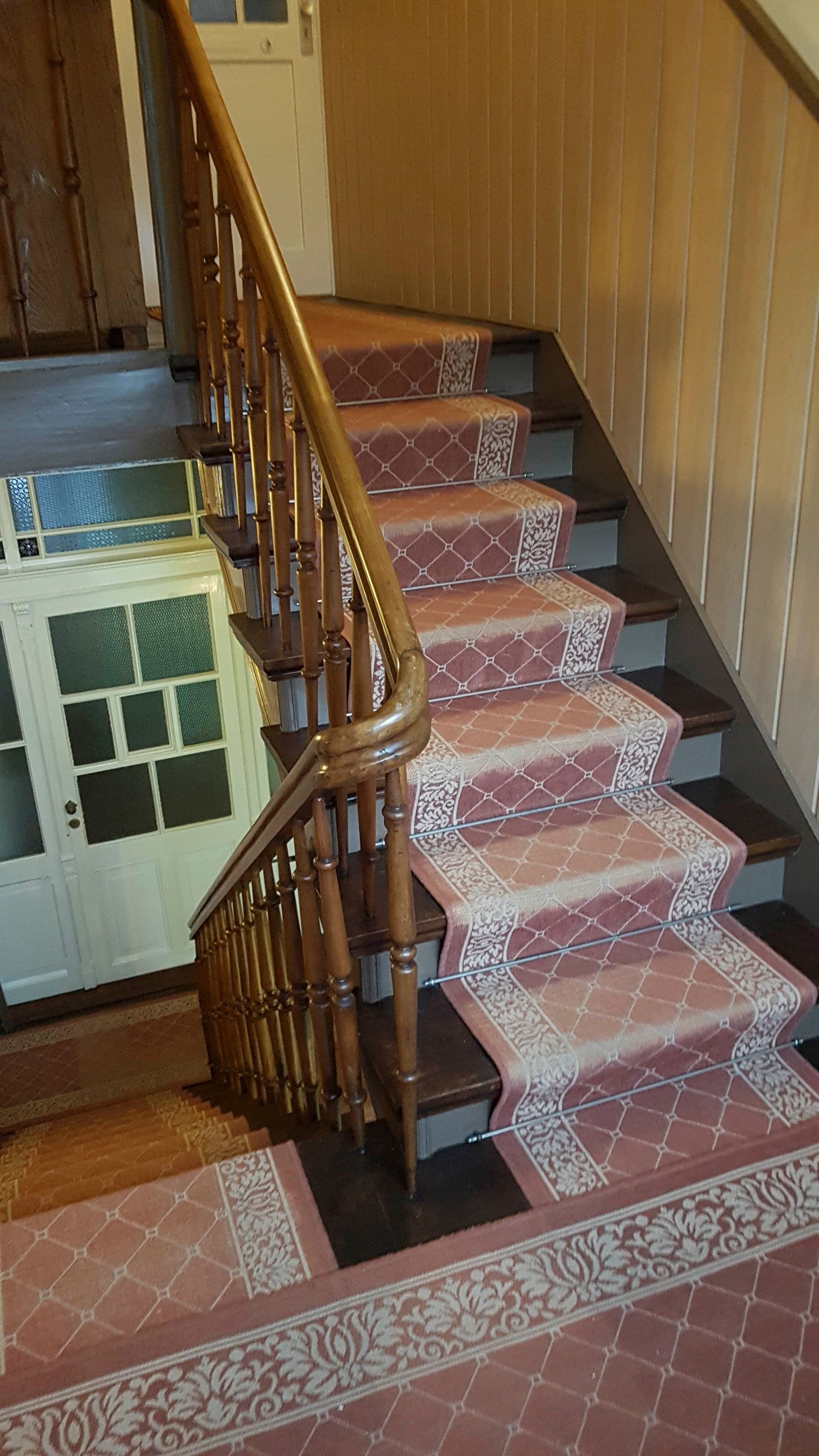 Eine Treppe mit einem rosa Teppich auf den Stufen und einem Holzgeländer.