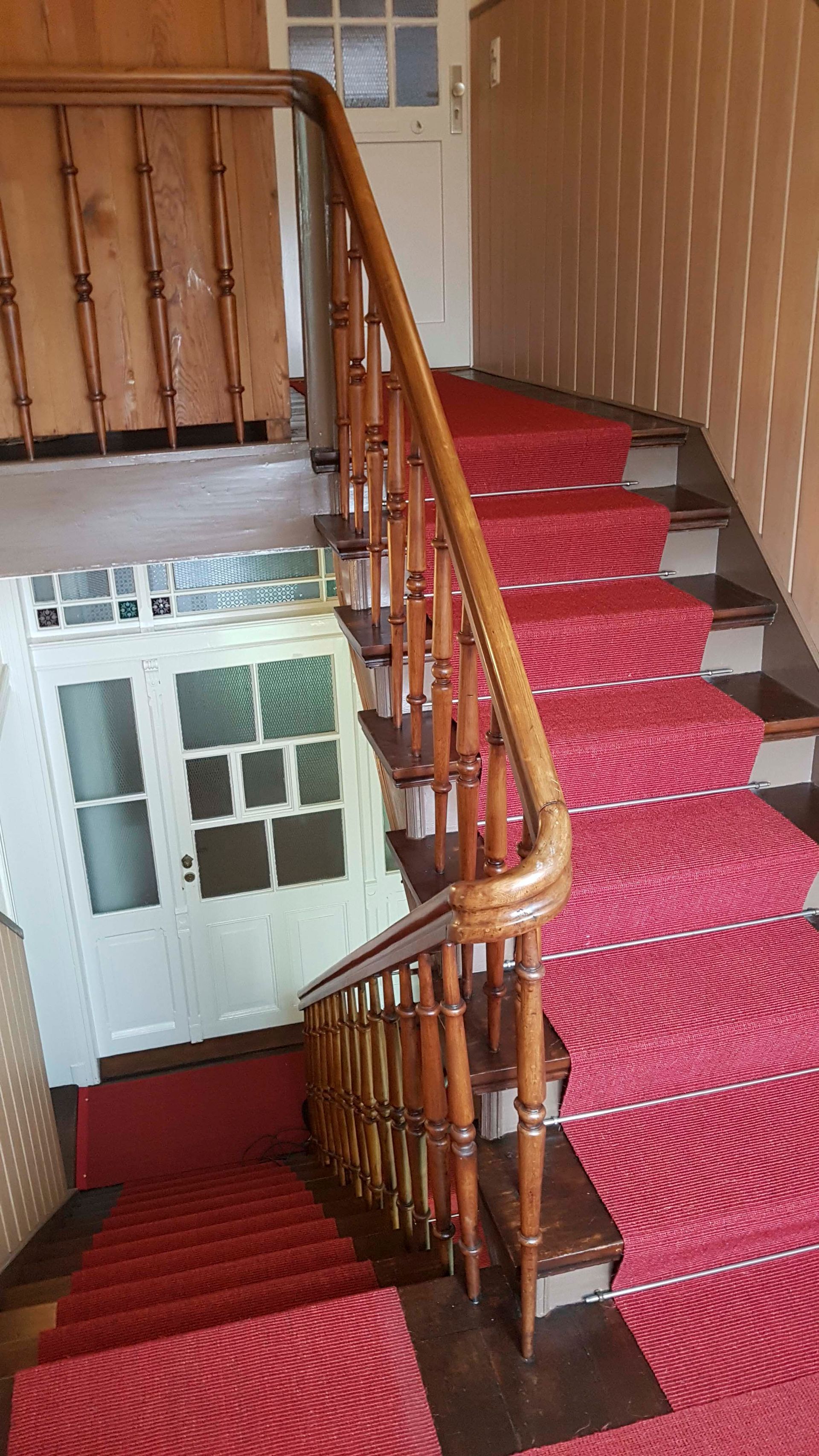 Eine Treppe mit Holzgeländer und rotem Teppich.