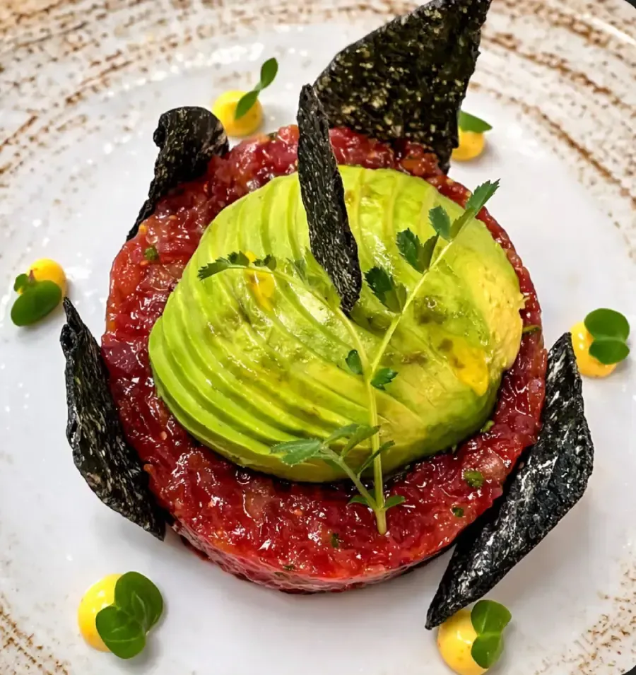 Huevos fritos con beicon servidos sobre una tortita de col dorada en un plato oscuro, espolvoreados con hierbas frescas.