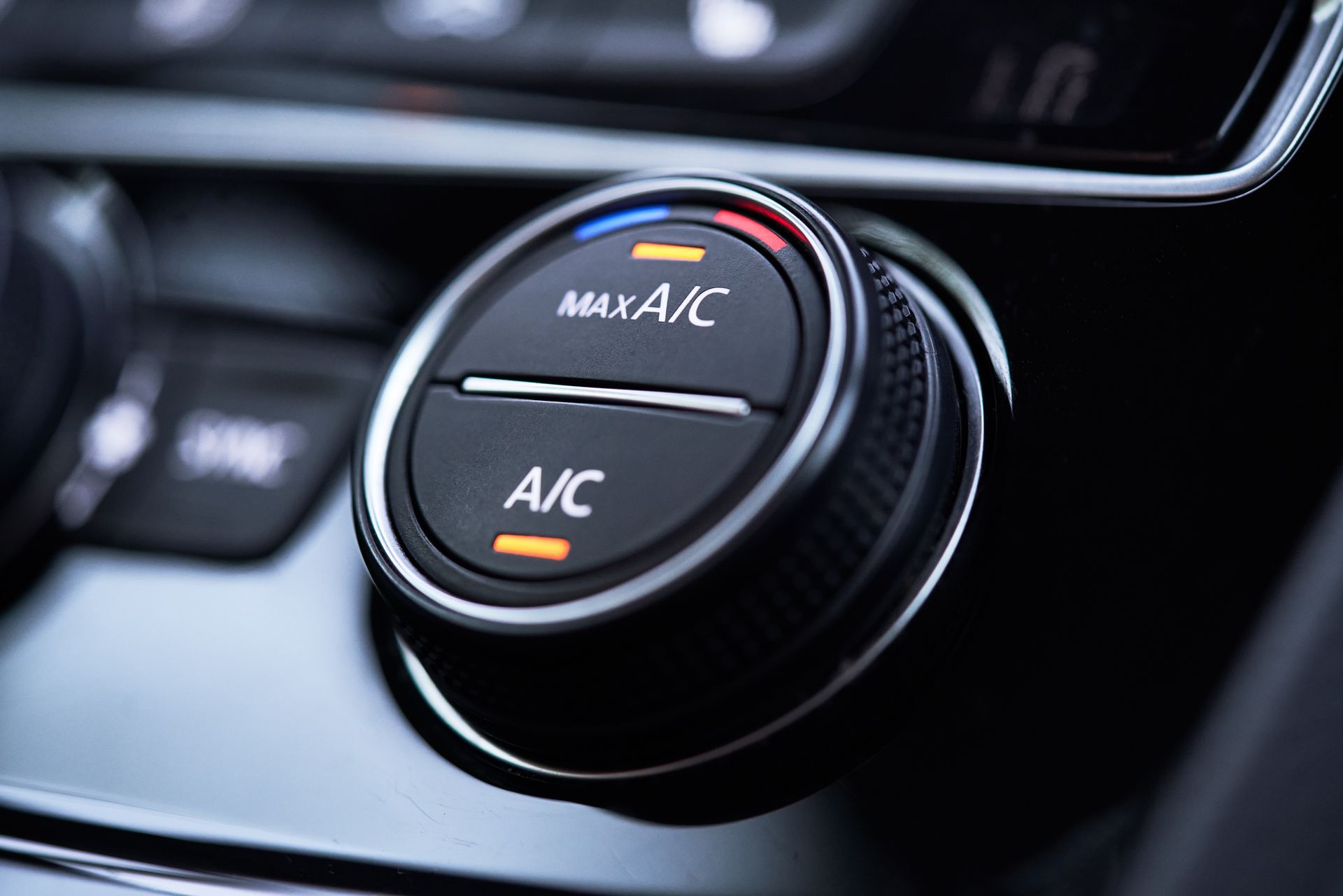 Bouton de commande de climatisation réglé sur A/C, avec voyant orange allumé sur un tableau de bord noir