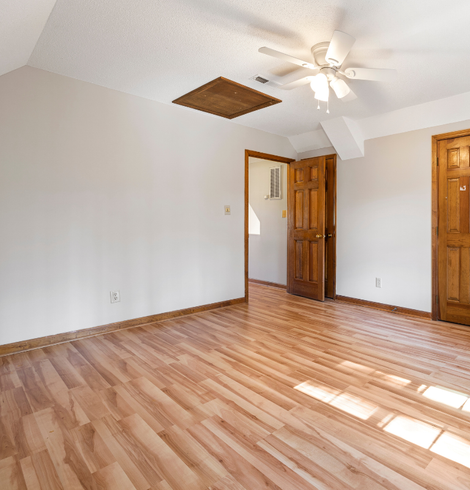 Une pièce vide avec du parquet et un ventilateur de plafond