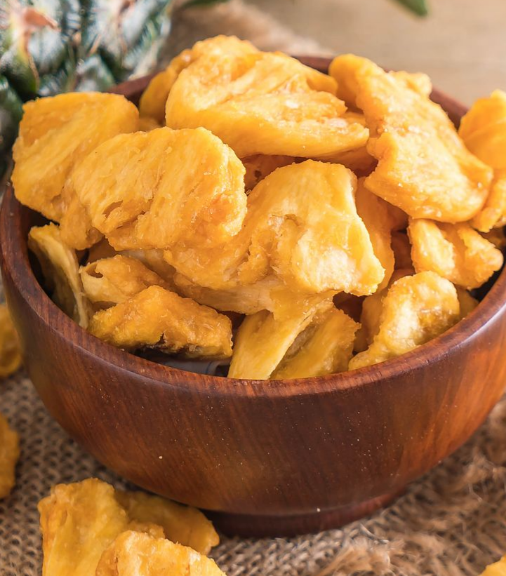 Main tenant un avocat à peau foncée sur une branche d'arbre, feuillage vert en arrière-plan.