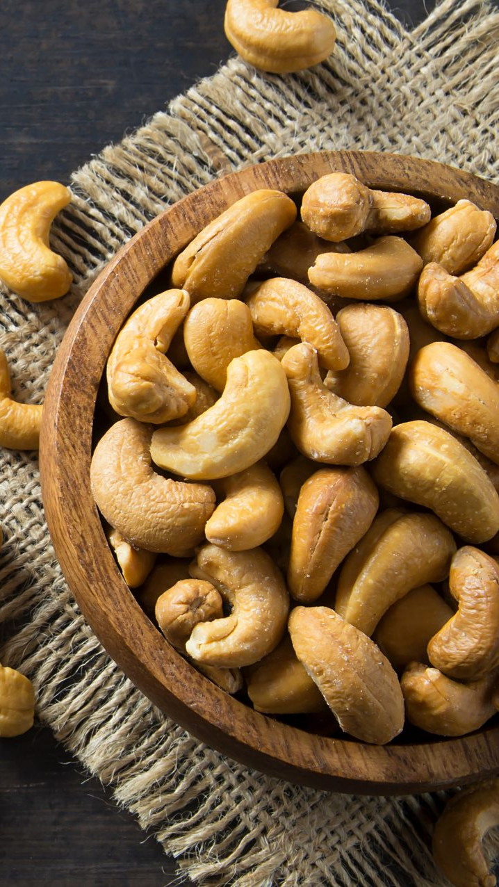 Main tenant un avocat à peau foncée sur une branche d'arbre, feuillage vert en arrière-plan.