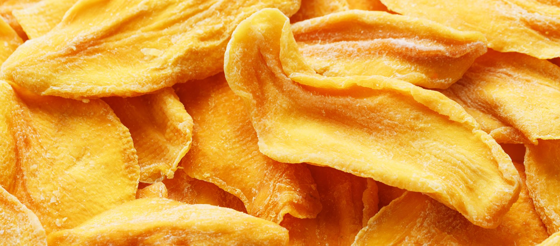 Tranches de mangue séchées, couleur jaune-orange, vue rapprochée.