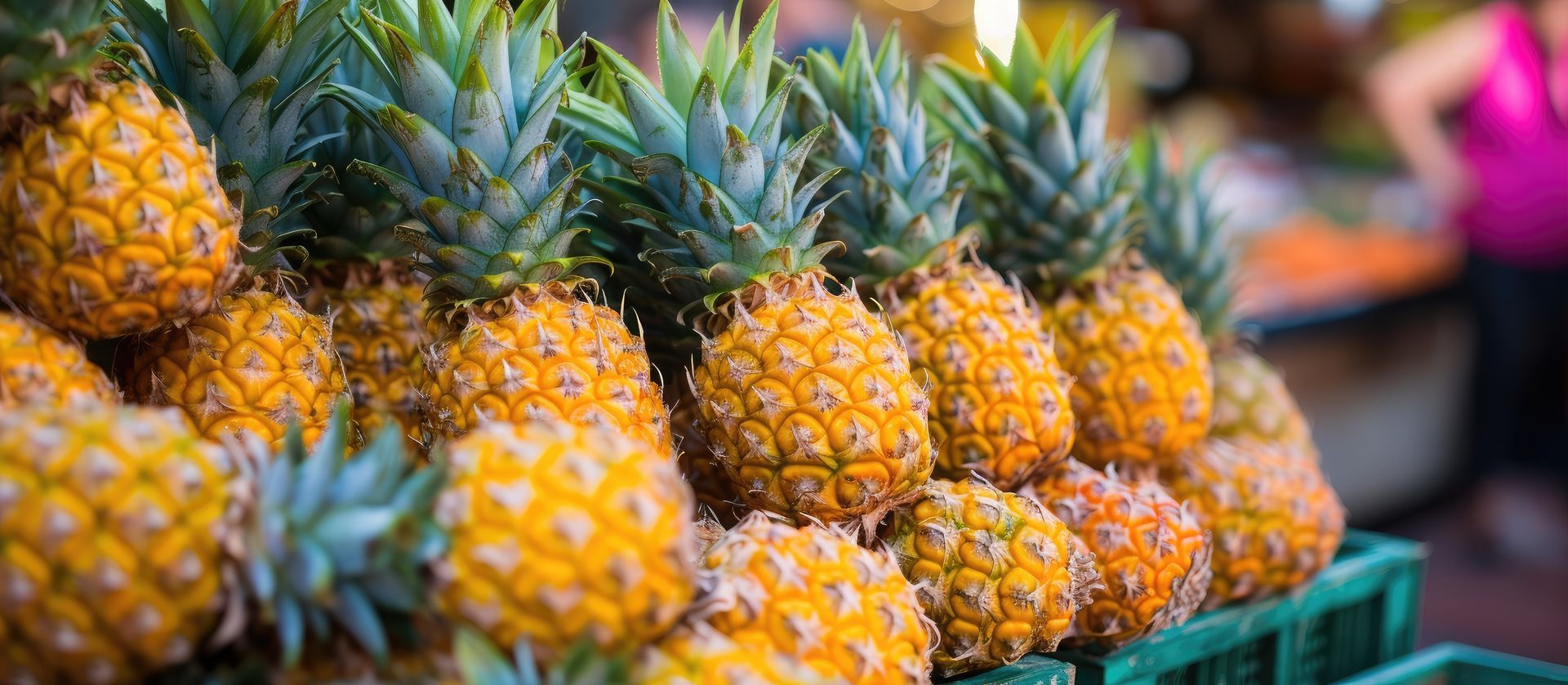 Pile d'ananas mûrs avec des feuilles vertes, sur un étalage dans un marché.