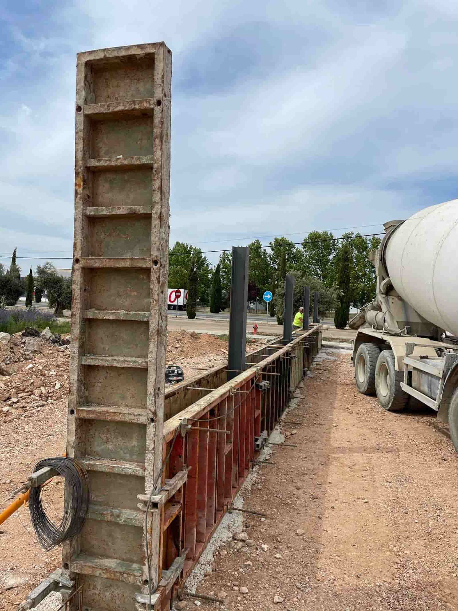 Encofrados de hormigón que se construyen para un muro con un camión hormigonera en un sitio de construcción al aire libre.