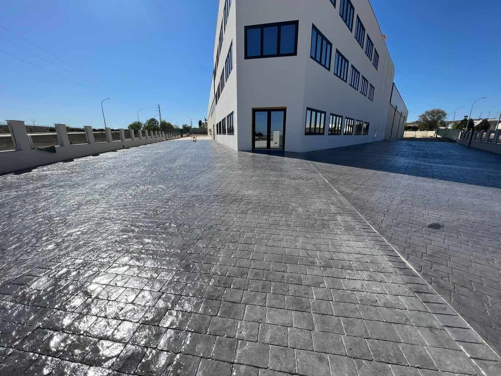 Edificio con pasarela de adoquines grises bajo un cielo azul.