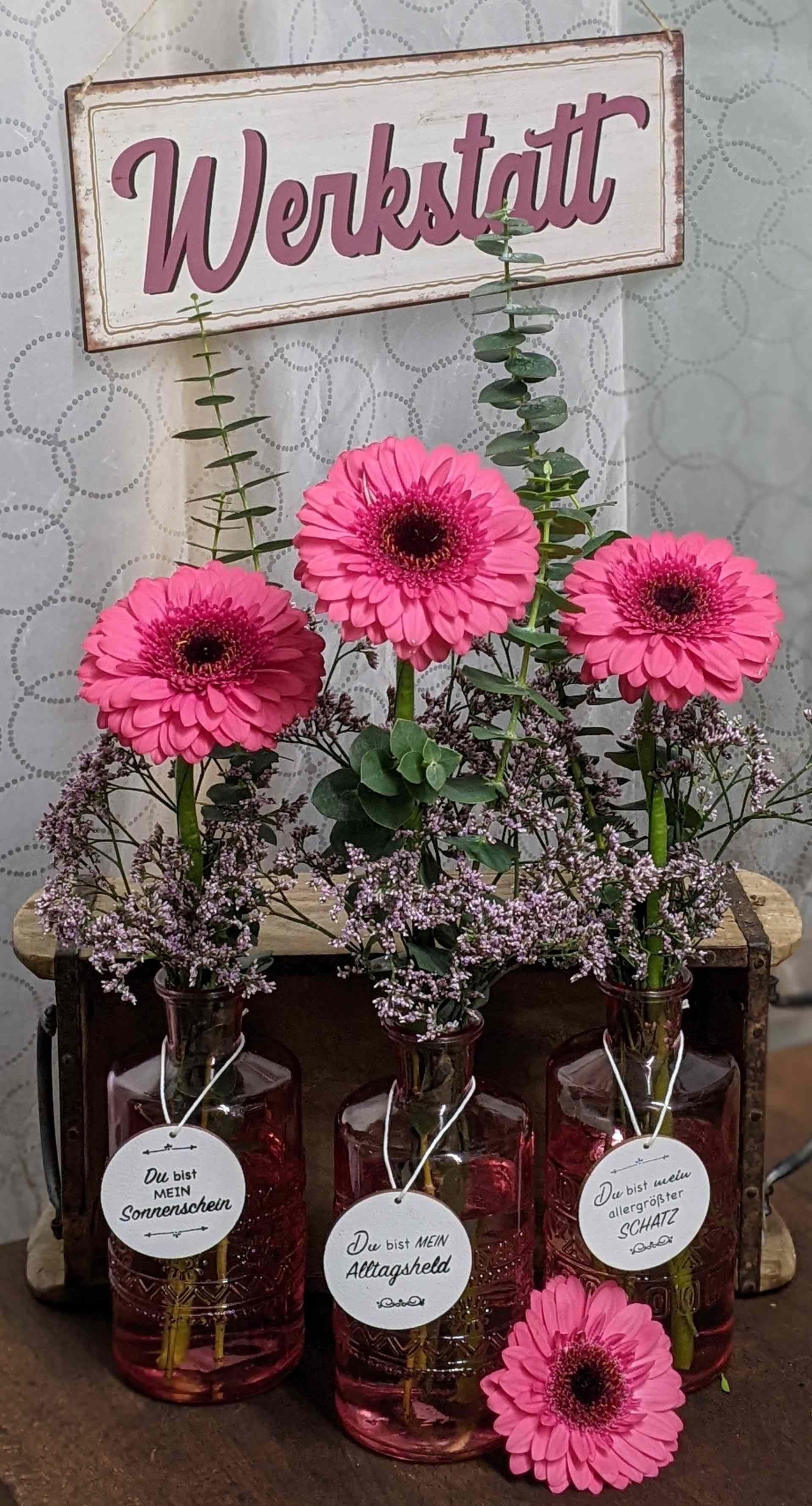 Drei rosa Vasen enthalten rosa Gerbera-Gänseblümchen.