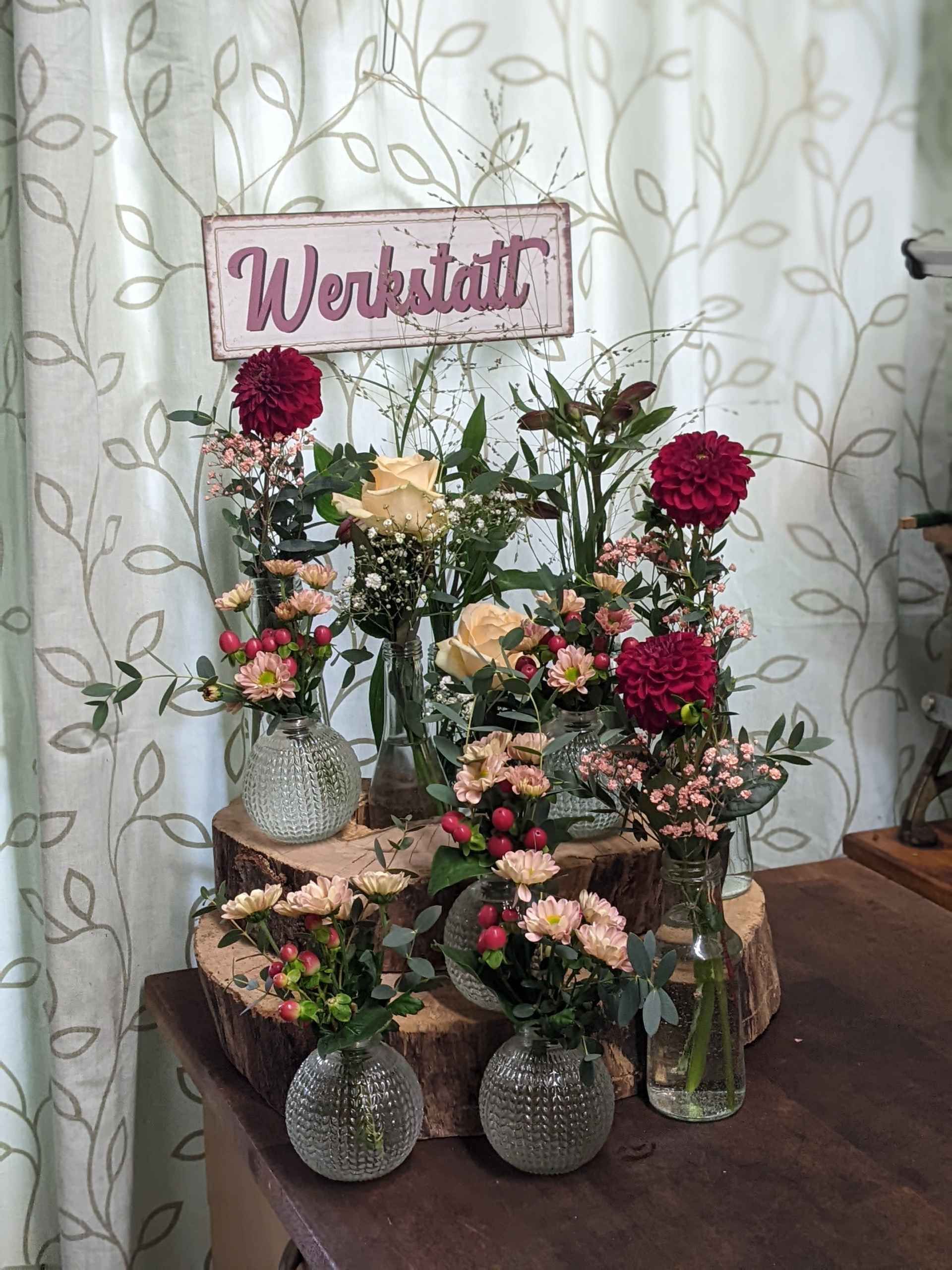 Tischset mit verschiedenen Blumengestecken für eine Werkstatt.